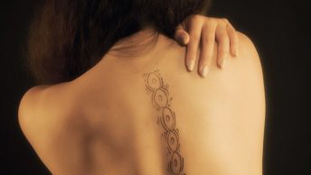 Mujer se toca la espalda en la que está dibujada las vértebras