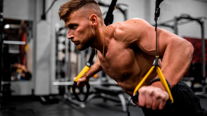 Qué es el TRX o entrenamiento en suspensión 1 Chico con TRX en un gimnasio
