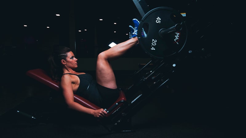 Chica haciendo press de piernas en el gimnasio