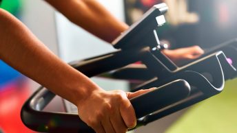 Deportista apoyado en el manillar de bici indoor