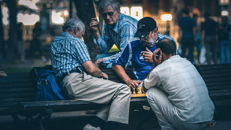 Señores jugando al ajedrez en un jardín