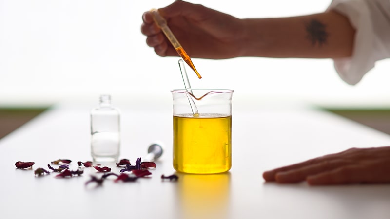 Manos en un laboratorio cosmético, añadiendo gotas de aceites esenciales