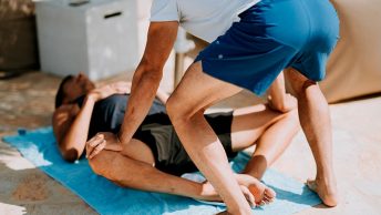 Entrenador ayuda a estirar a un lesionado
